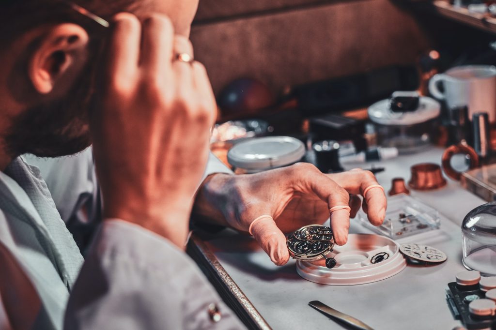 mature-clockmaster-is-fixing-old-watch-for-a-customer-at-his-busy-repairing-workshop